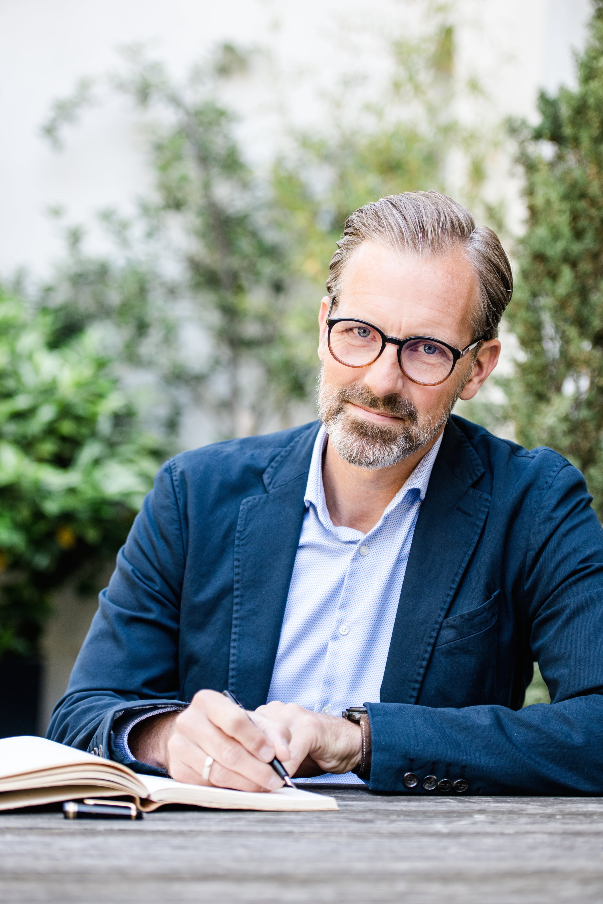 Kay Rosenbaum schreibt in ein Notizbuch im Garten